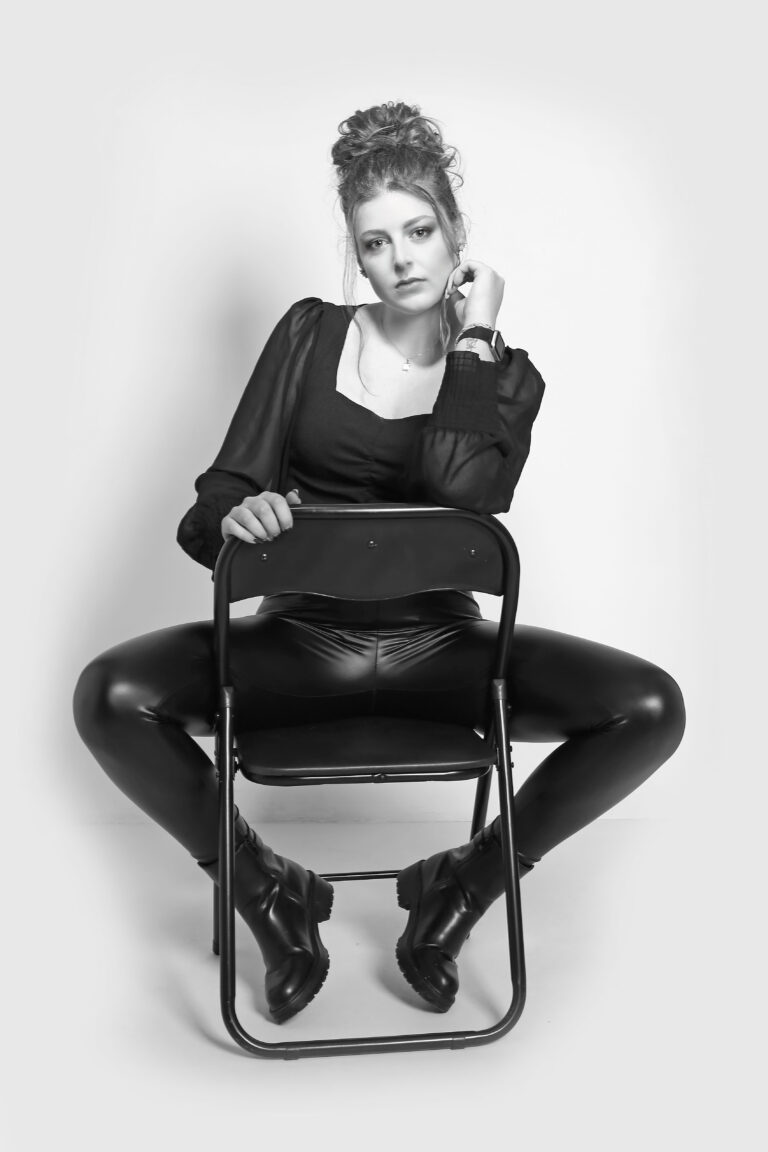 Photo noire et blanc en studio de femme rousse sur une chaise.